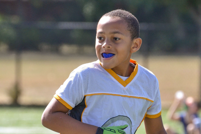 a child playing sports with a mouth guard.